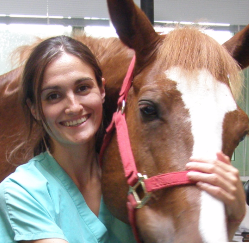 A woman in scrubs standing next to a horse.