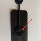 A black wall mounted shower head with an arrow pointing to the top.